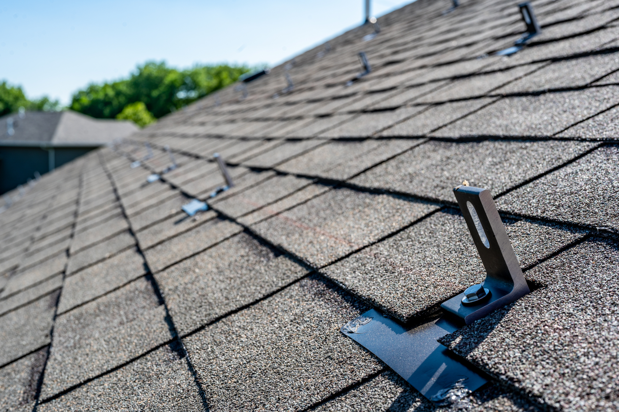 Residential asphalt shingle roof with metal anchors installed for the installation of a solar panel rail and racking system