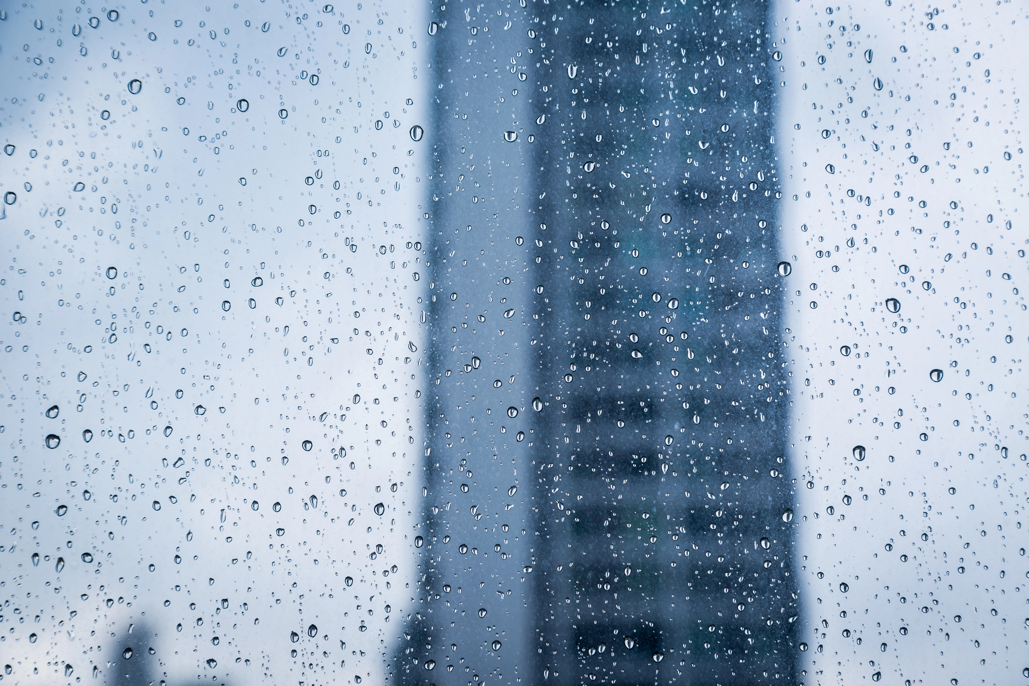 window with rain and building needing storm damage repair